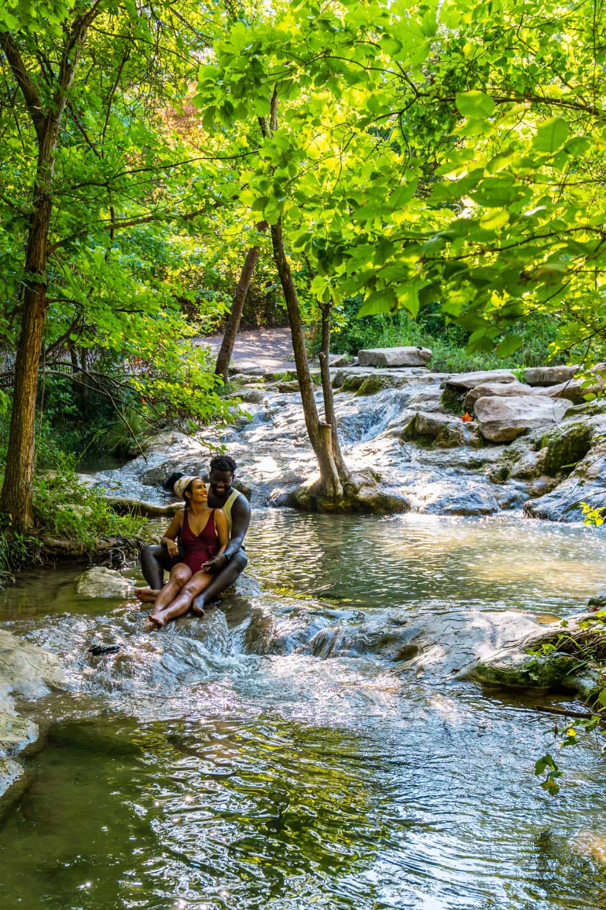 Couple sitting in the stream under trees