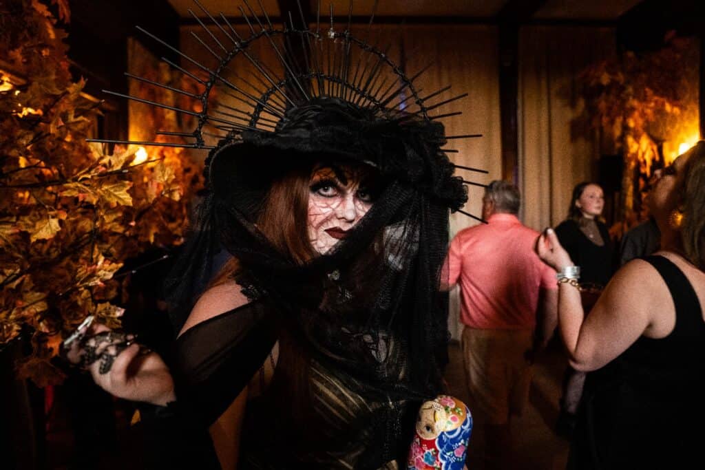 A woman with an elaborate witch costume on and a painted face