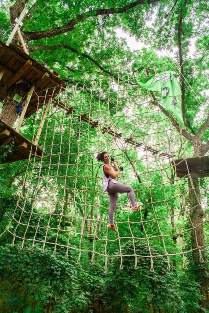 Woman climbing up a rope ladder wall