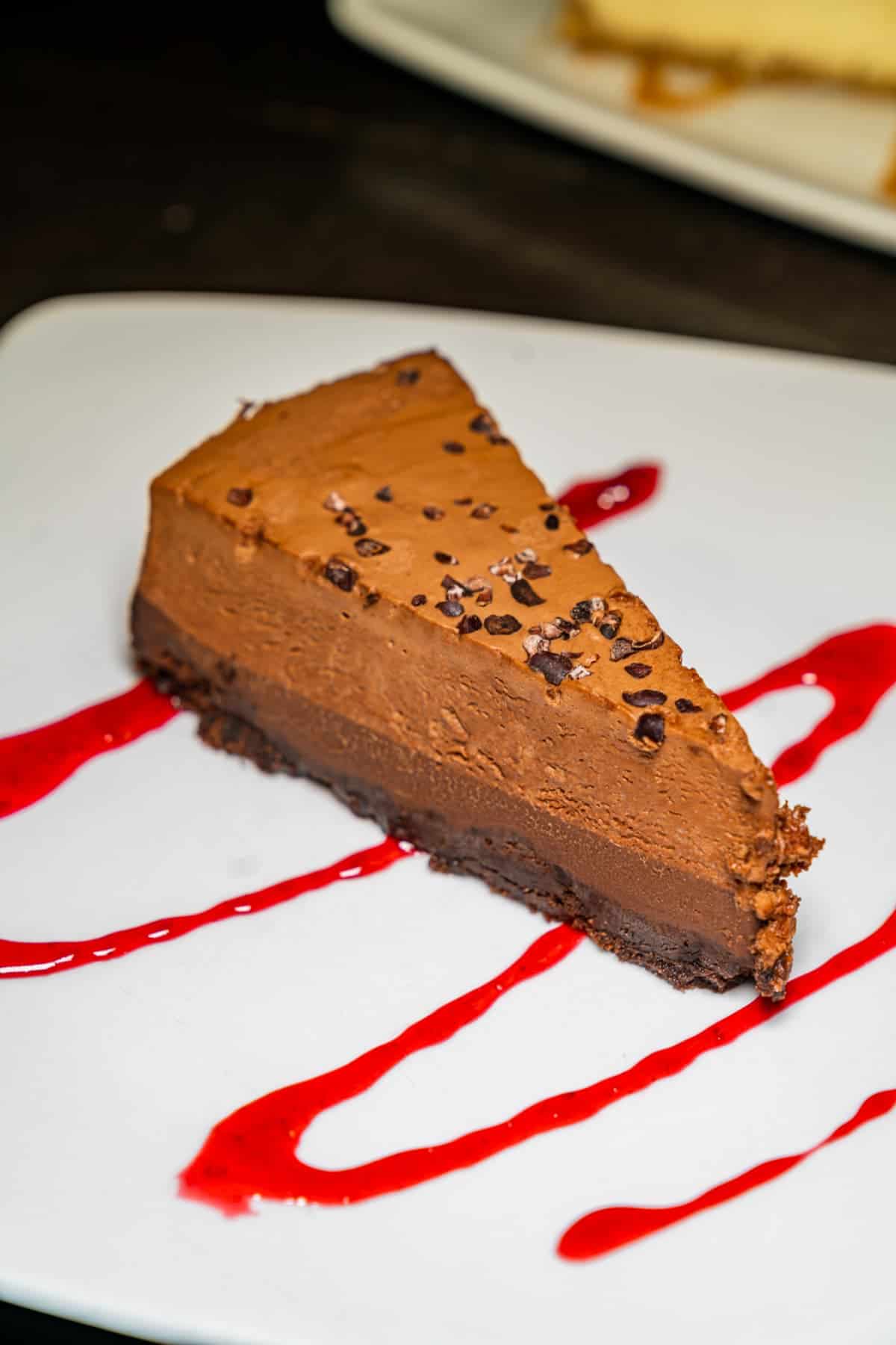 Slice of chocolate pie with raspberry reduction drizzled on the plate