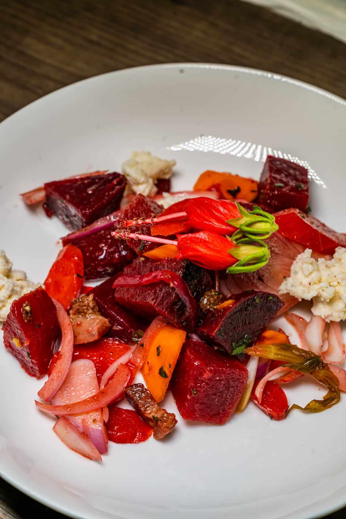 Plate of beets, carrots, and goat cheese with an edible flower on top