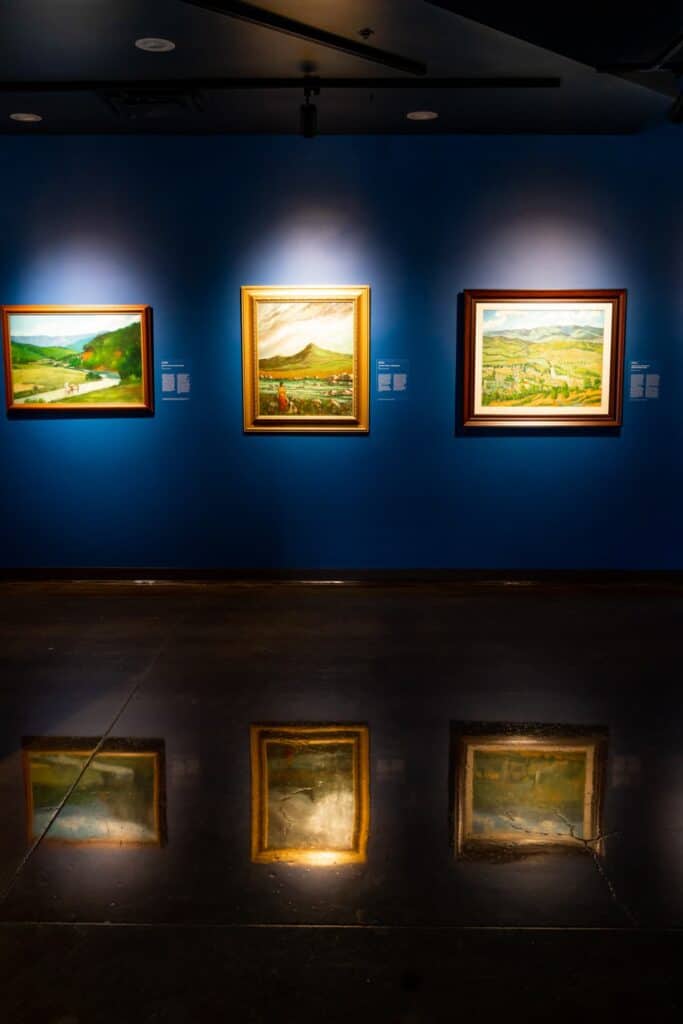 Three canvases on display inside of "Nostalgia for my Island" exhibit