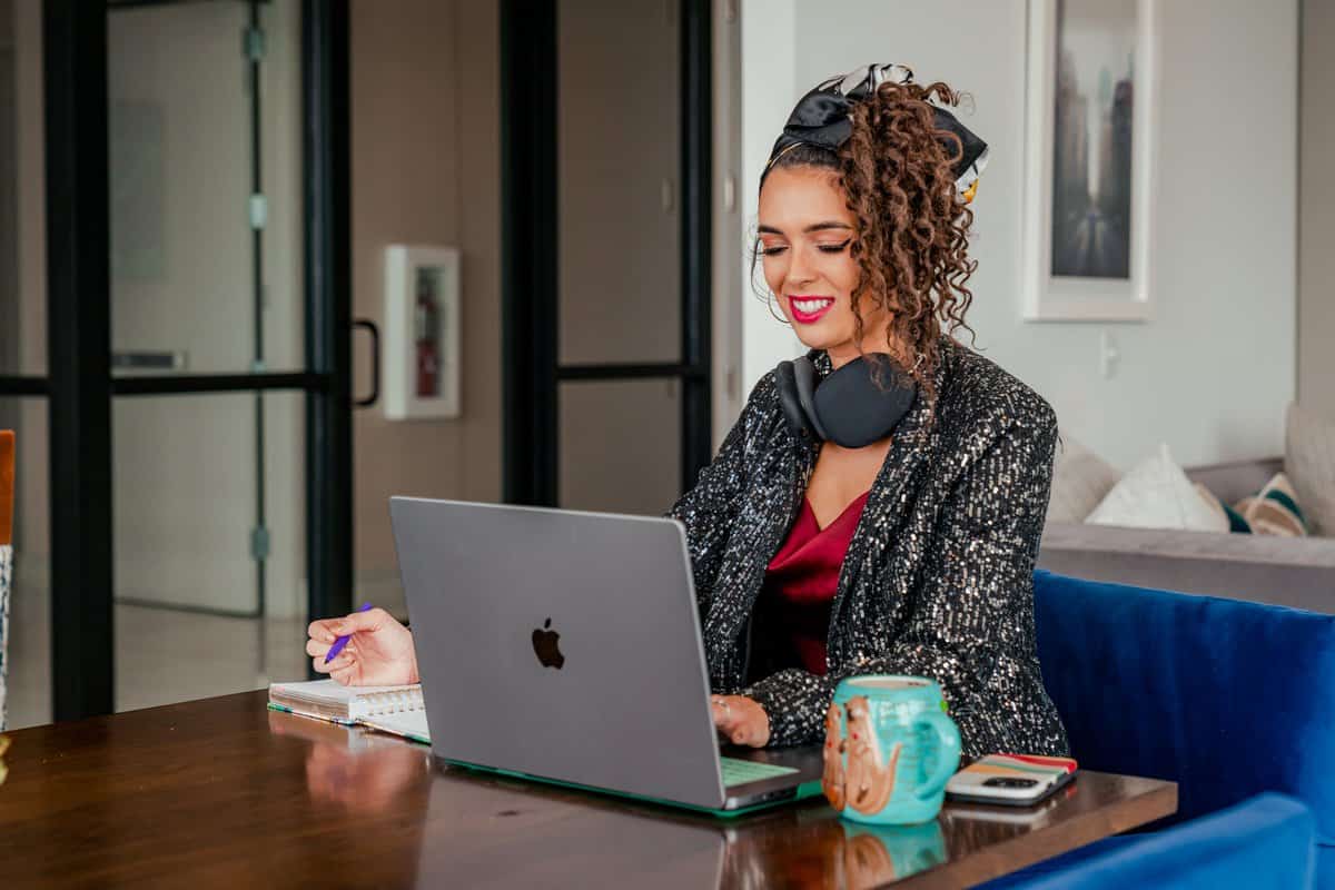  A woman with headphones is seated at a desk, engaged with her laptop