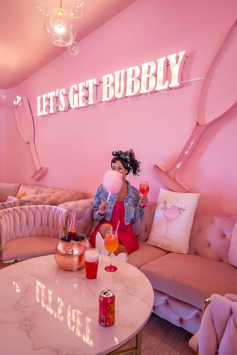 Woman sitting on pink couch in pink room with matching pink walls and furniture.