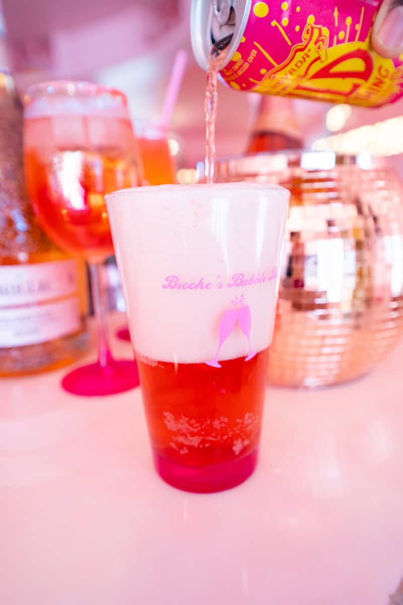 A glass being filled with a pink drink.