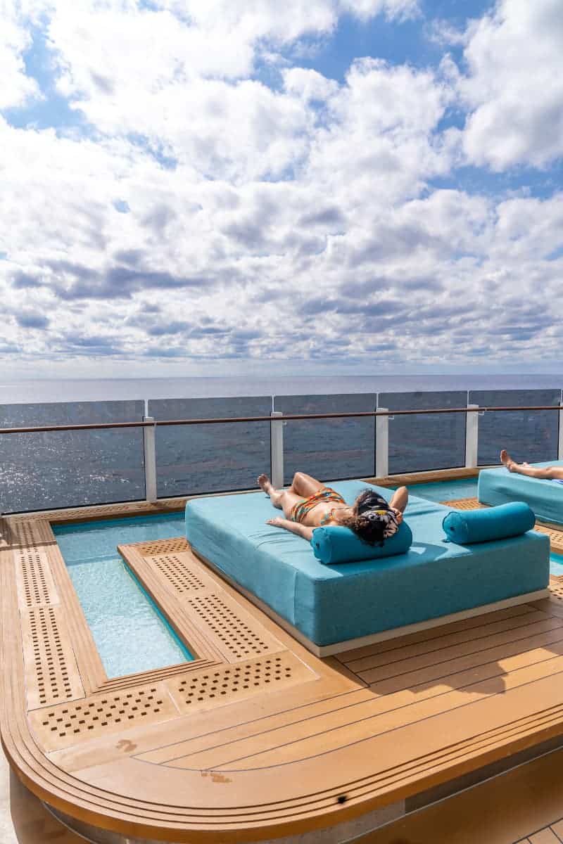 Woman laying out on a bed on the pool deck