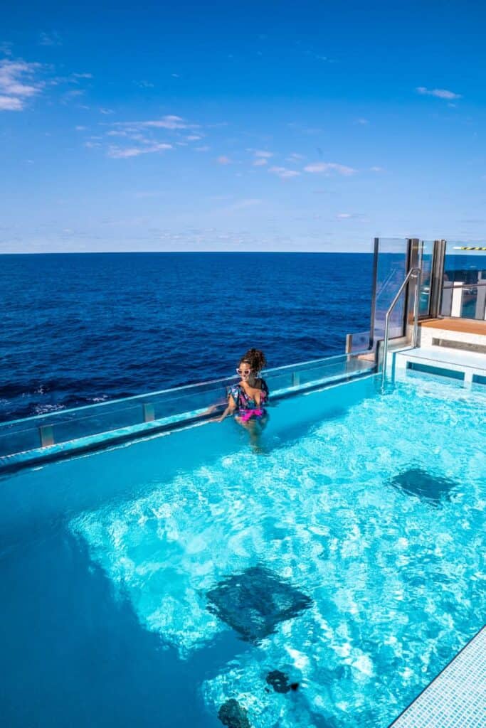 Woman in an infinity pool with the ocean in the background