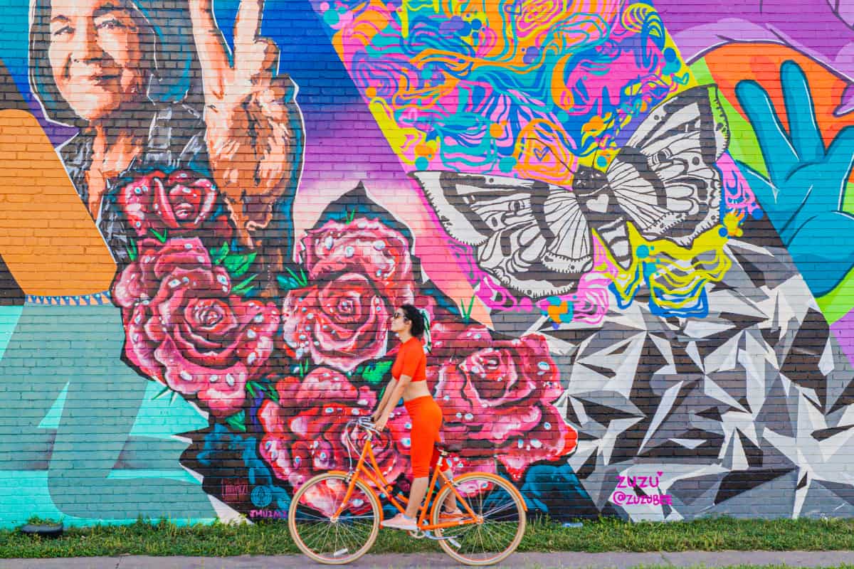 Woman on a bike in front of a mural