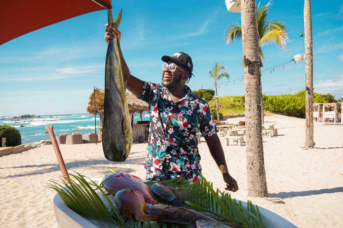  A man on the beach displays a freshly caught fish