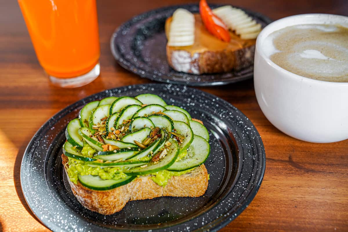 Plate of avocado toast and cucumber and a cup of coffee