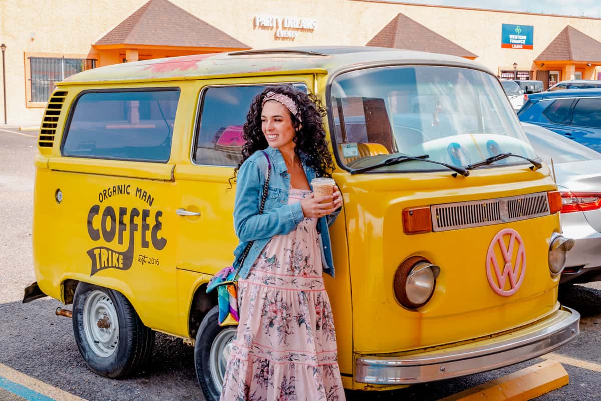 Woman standing next to a retro, yellow bus