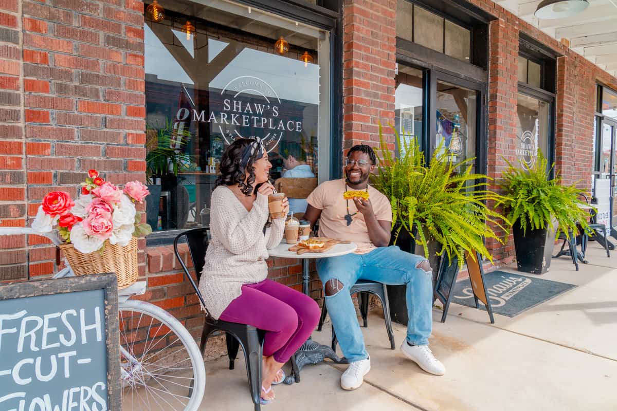 Couple alfresco drinking coffee and eating a snack outside a coffee shop