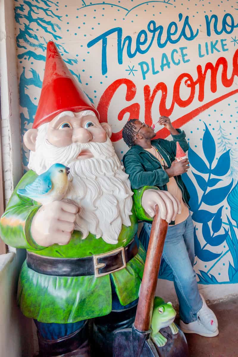 Man eating Gnome Cone in front of a giant gnome statue