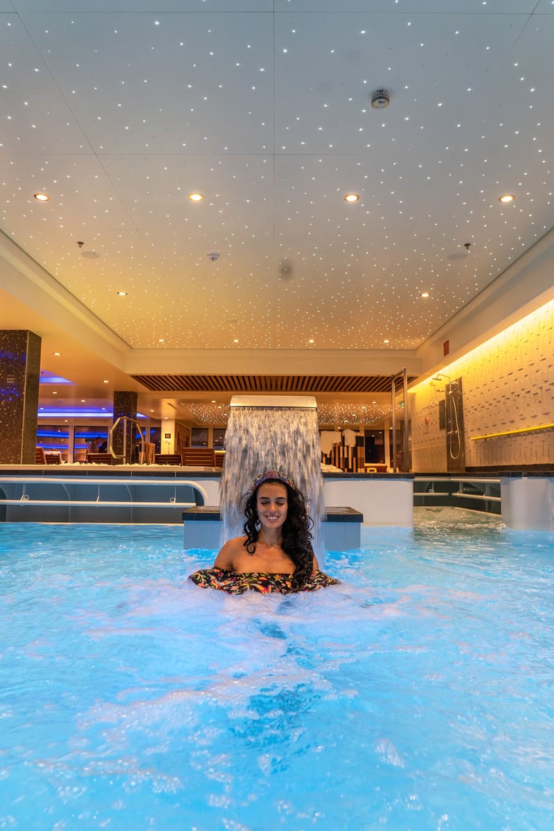 Woman standing under a water feature inside an indoor pool