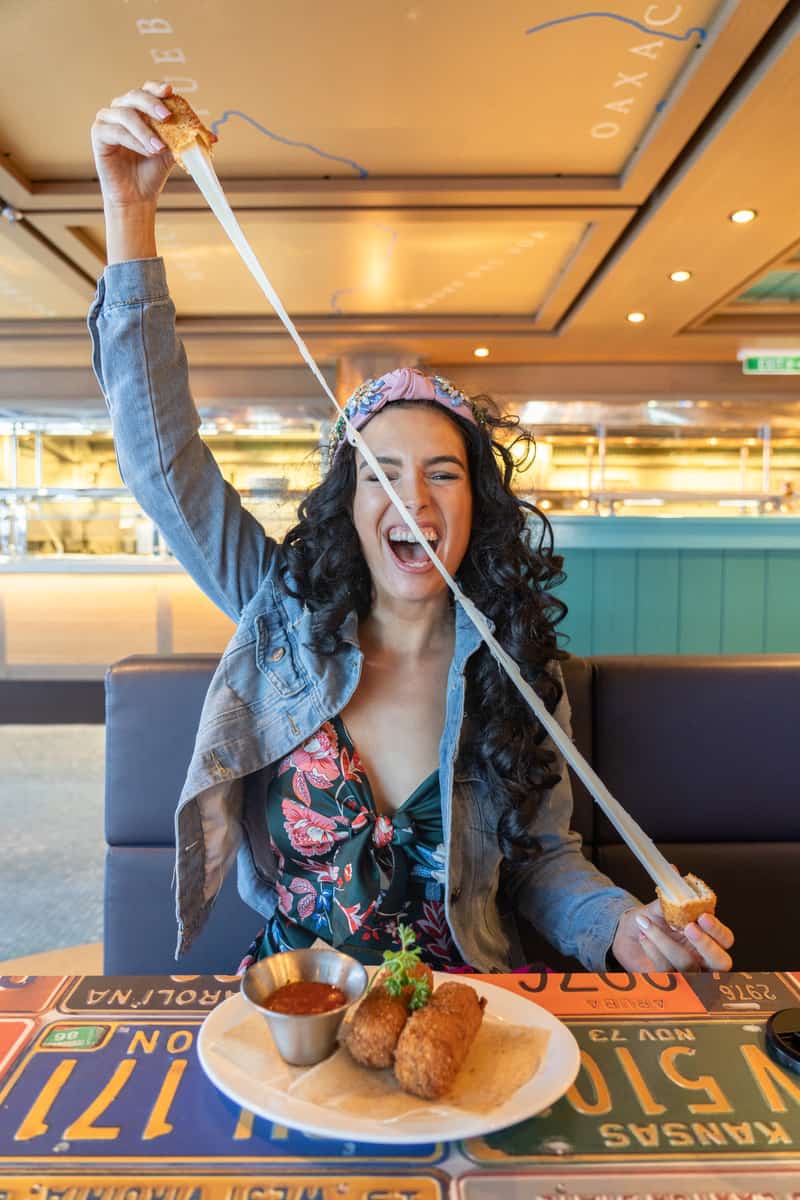 Woman showing off a huge cheese pull at a restaurant