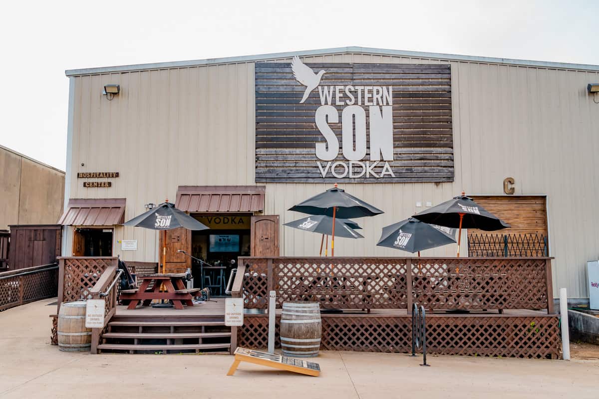 Exterior of Western Son's Distillery with patio and cornhole