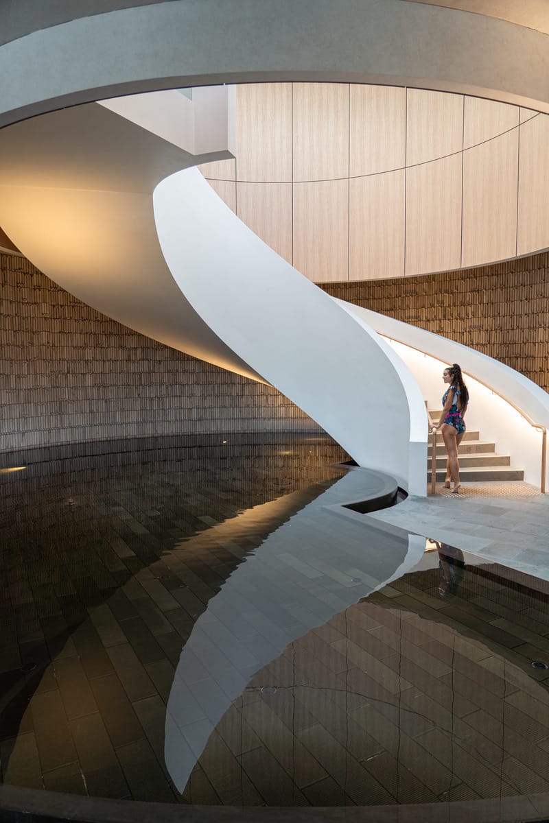 Woman standing on an elegant staircase with a reflective pool beneath it