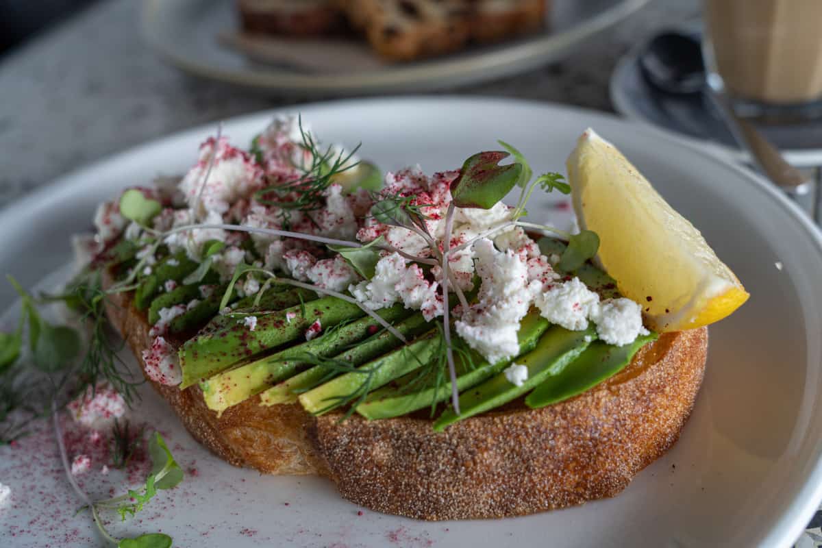 Avocado toast on a plate with a lemon wedge