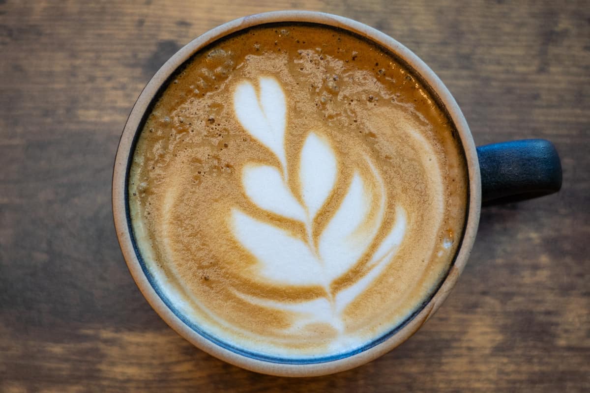 Latte in a coffee mug with floral latte art on top