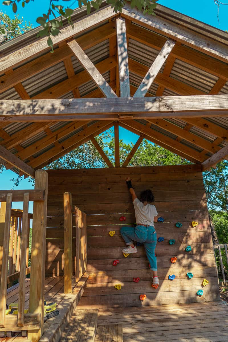 Woman climbing on a small, covered, rock climbing wall