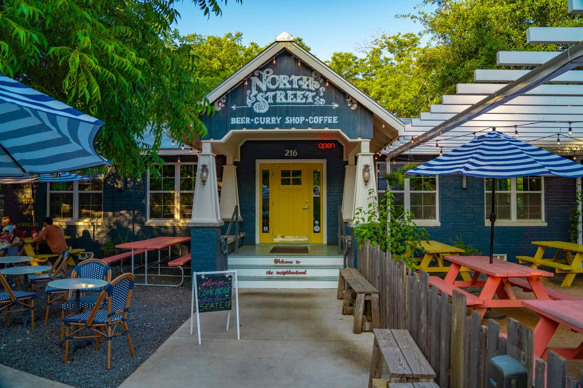 Storefront with a yellow door and picnic tables