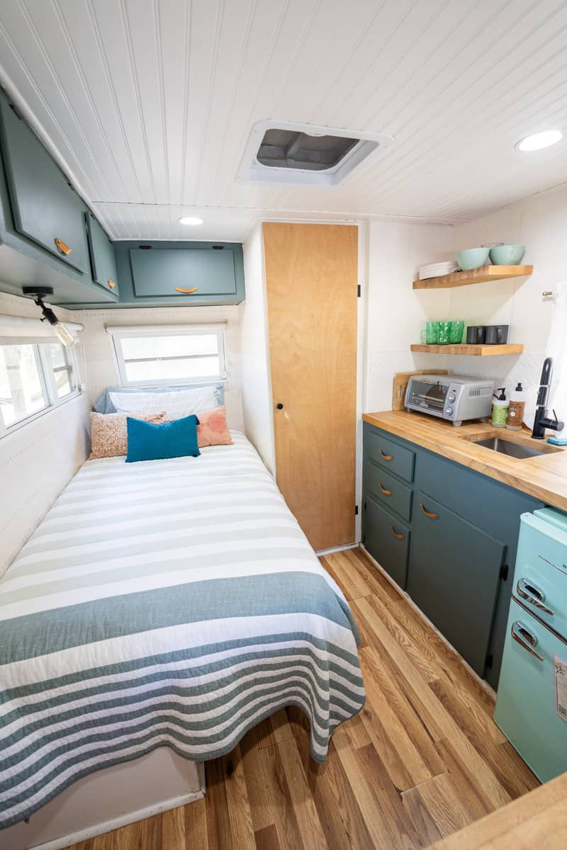 Bed inside the camper with storage and a kitchenette