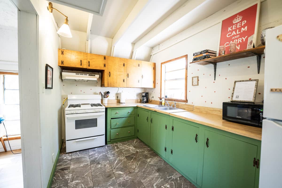 Litchen with green cabinets and equipped with a full fridge, microwave, and oven