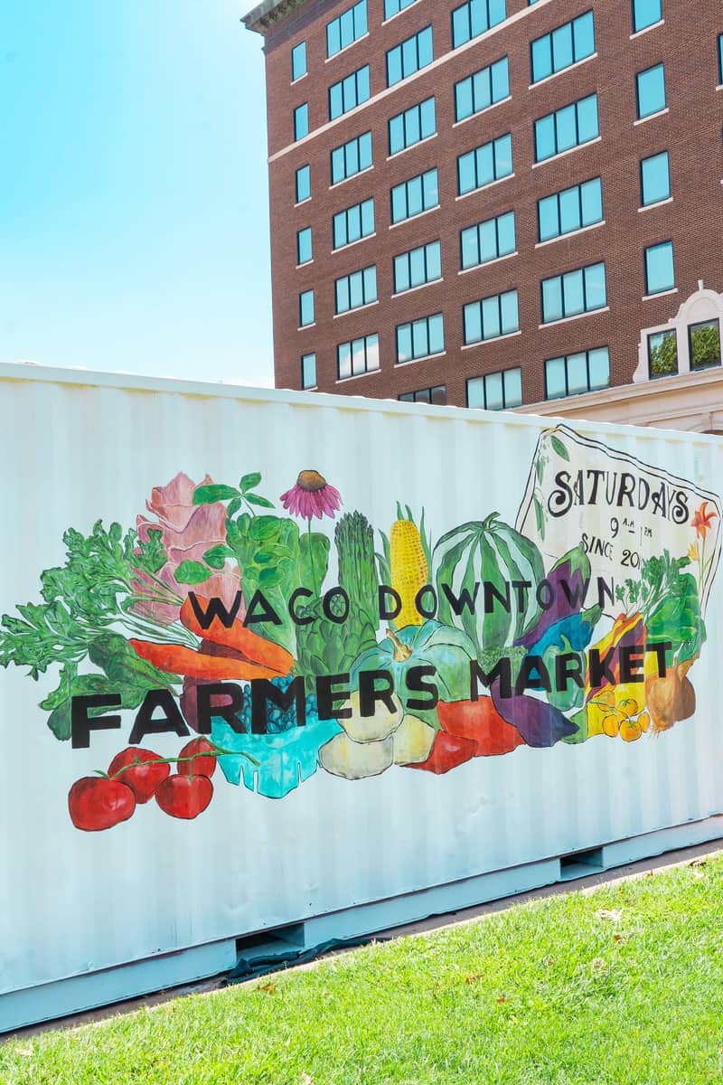 Mural on the side of a storage container that says "Waco Downtown Farmers Market" with paintings of vegetables in the background