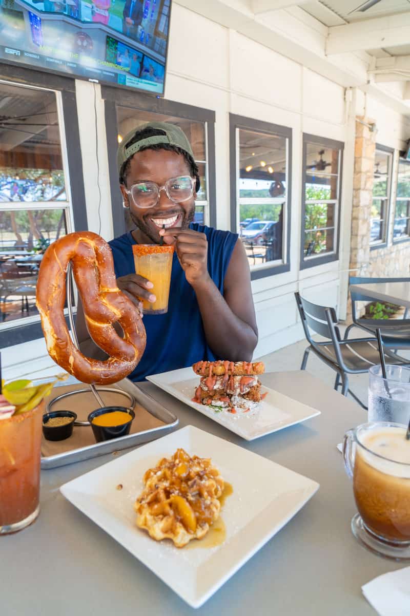 A man dining with pretzels, waffles and drinks