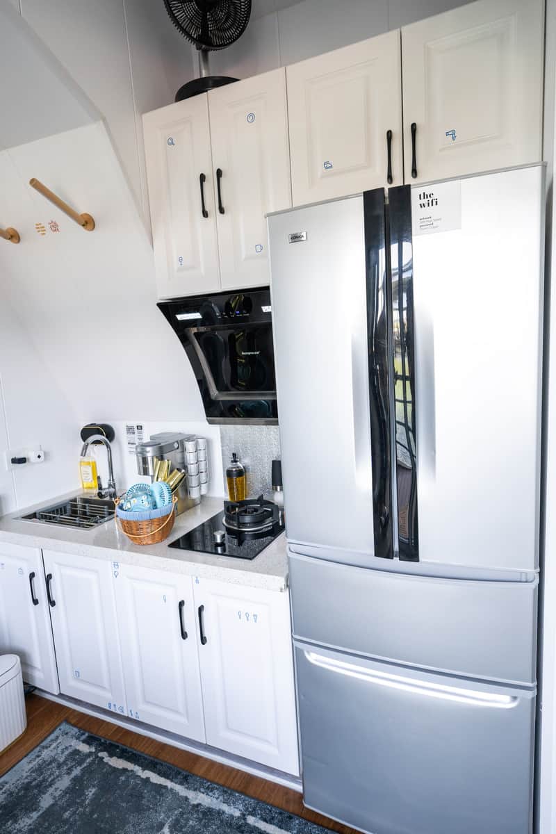 Modern kitchen interior with white cabinets, stainless steel fridge, and black countertops.