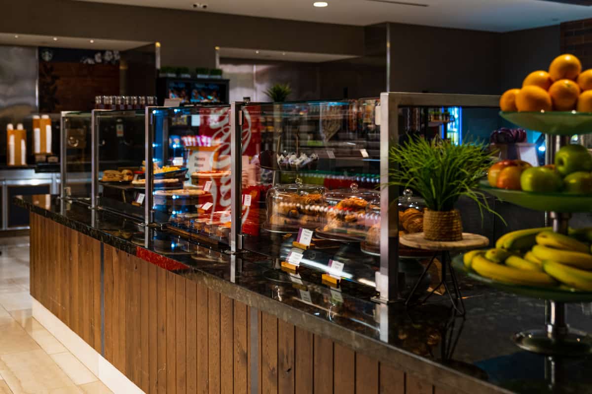 Hotel buffet counter with pastries and fresh fruit on display.