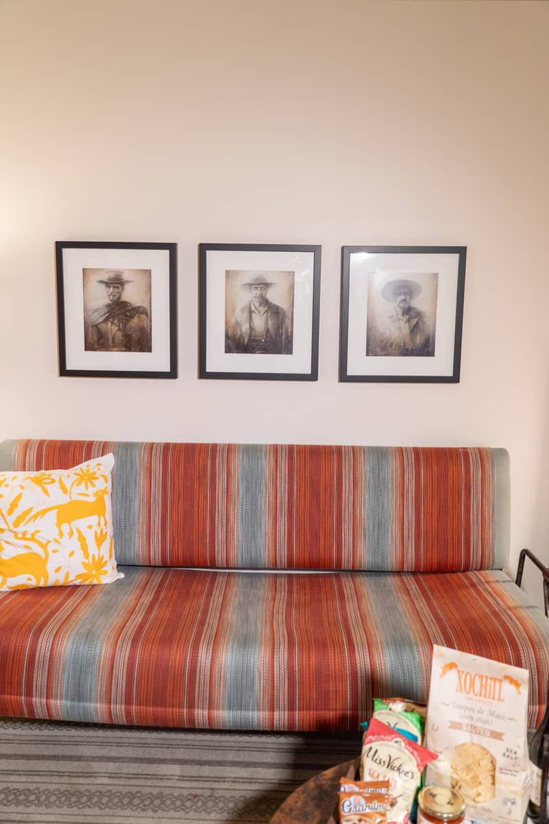 Striped couch with patterned pillows and black and white framed photos above it