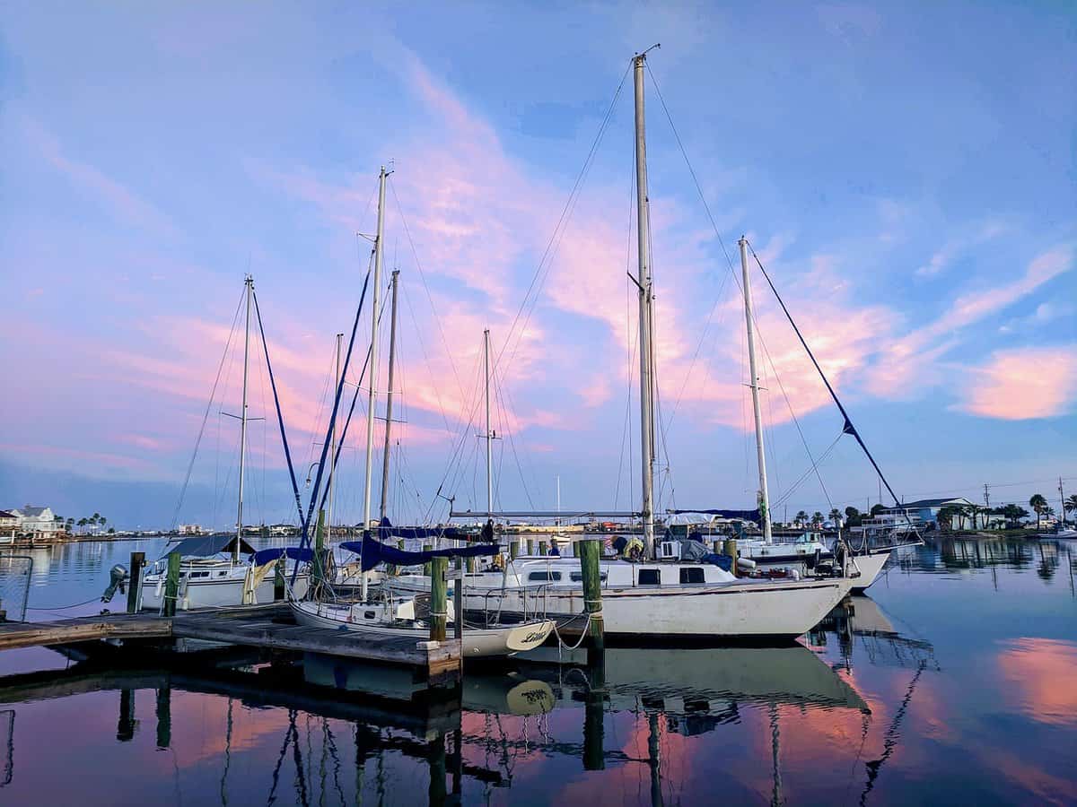 Sailboats docked in calm marina at sunset