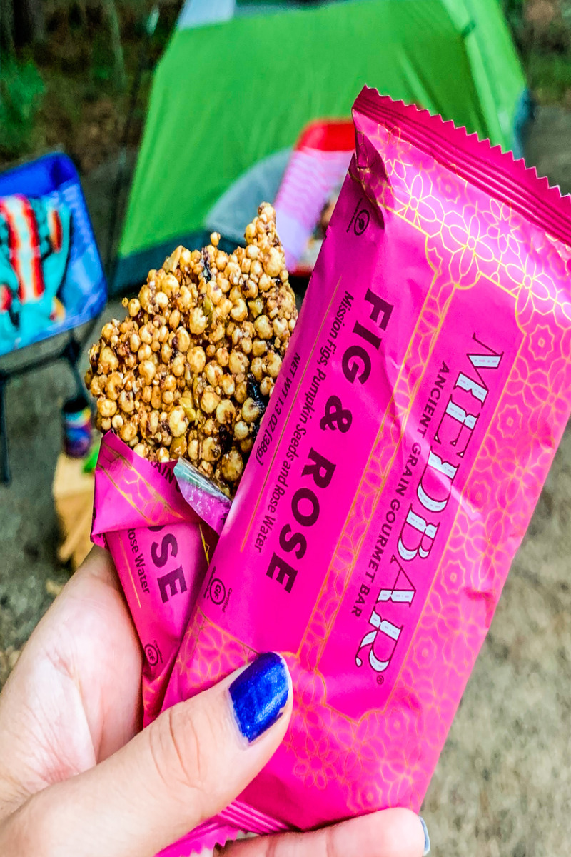 a hand holding a pink wrapper with a bag of popcorn