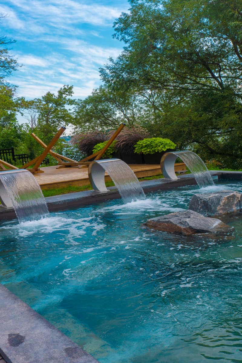 An outdoor pool with water fountains at the side