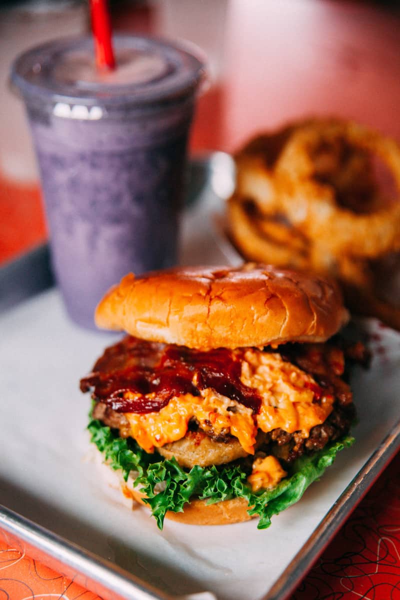 a burger with a drink in the background