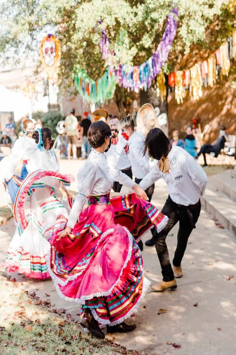 Ballet folklorico dancers dancing on the street surrounded by festive decor