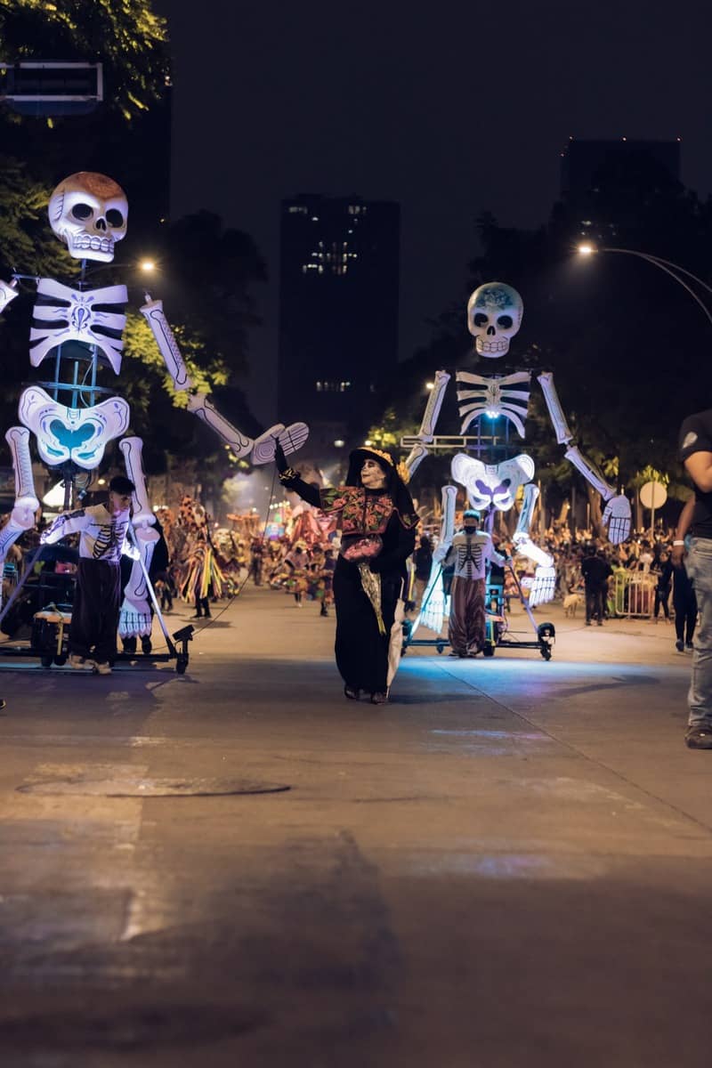 Nighttime parade with huge skeleton marionettes and a woman in a Catrina costume leading the way