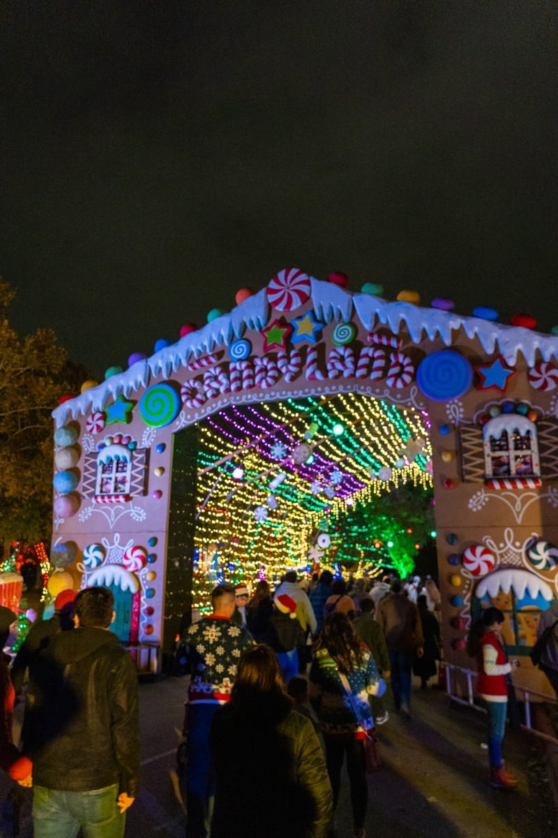 A festive gingerbread house entrance to a walkway of lights.