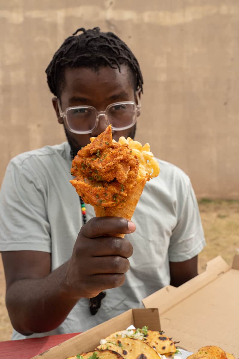 A man holding the Pimpin' Mac & Cheese with Waffle - buffalo chicken and homemade mac and cheese stuffed in a handcrafted cayenne waffle cone and topped with crispy bacon.