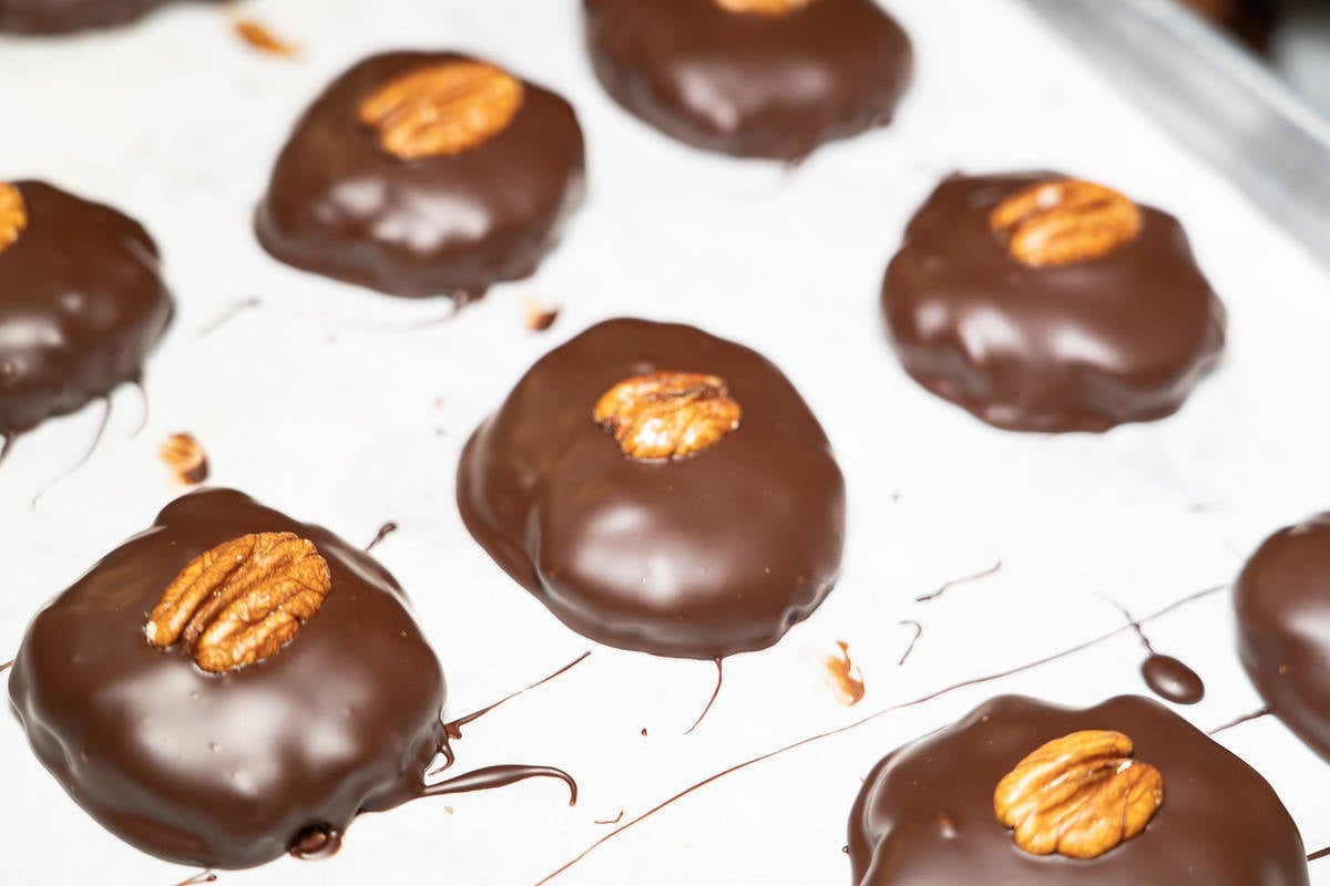 Chocolates on a sheet pans with pieces of pecan in the center