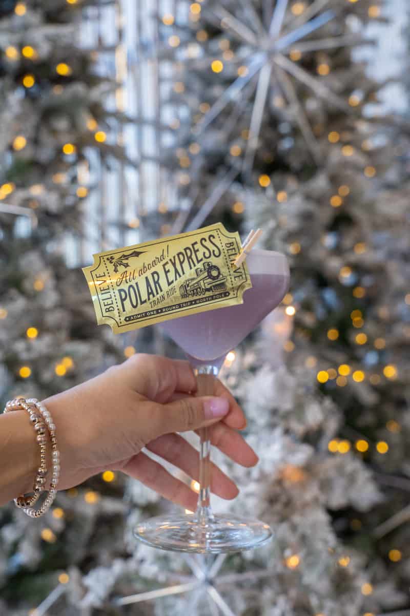 A holiday drink with a polar express ticket on glass