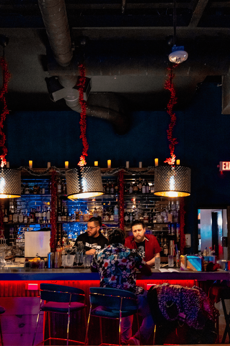 A vibrant bar scene with patrons gathered around the counter, sipping drinks and engaging in lively conversations.