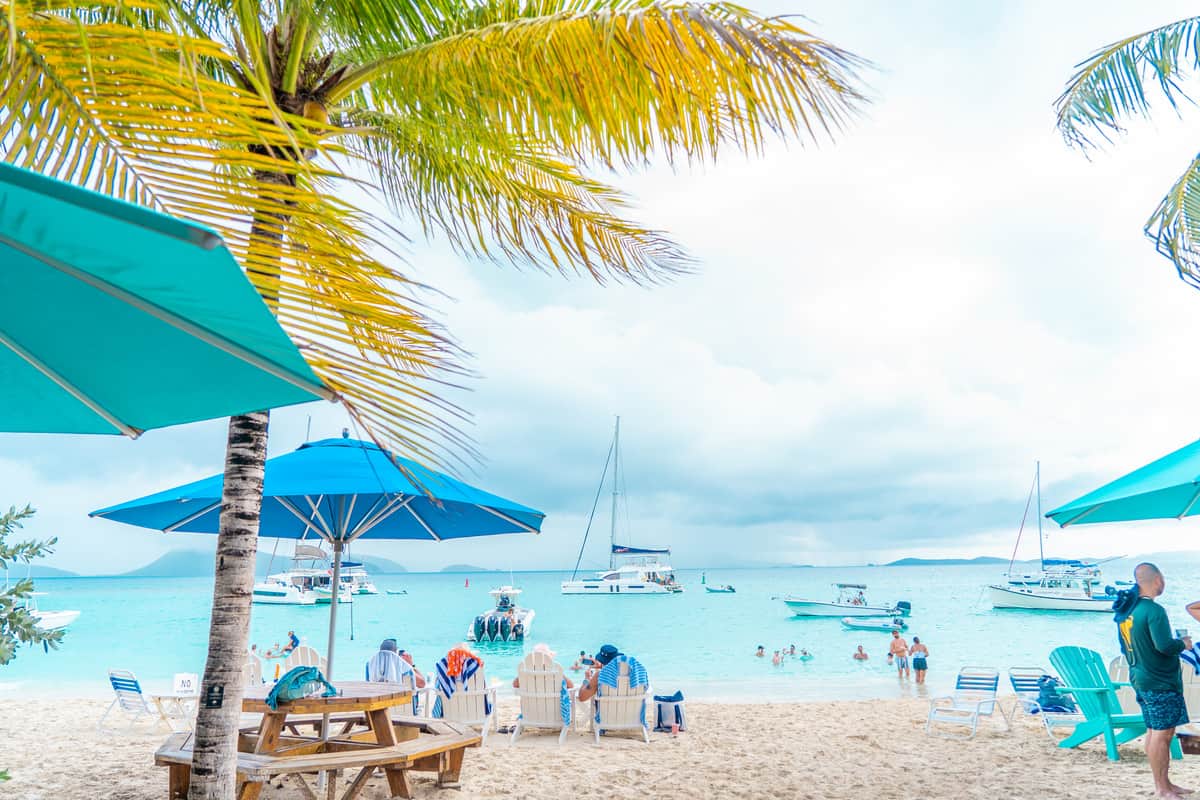 a beach with people and boats - sailing the british virgin islands
