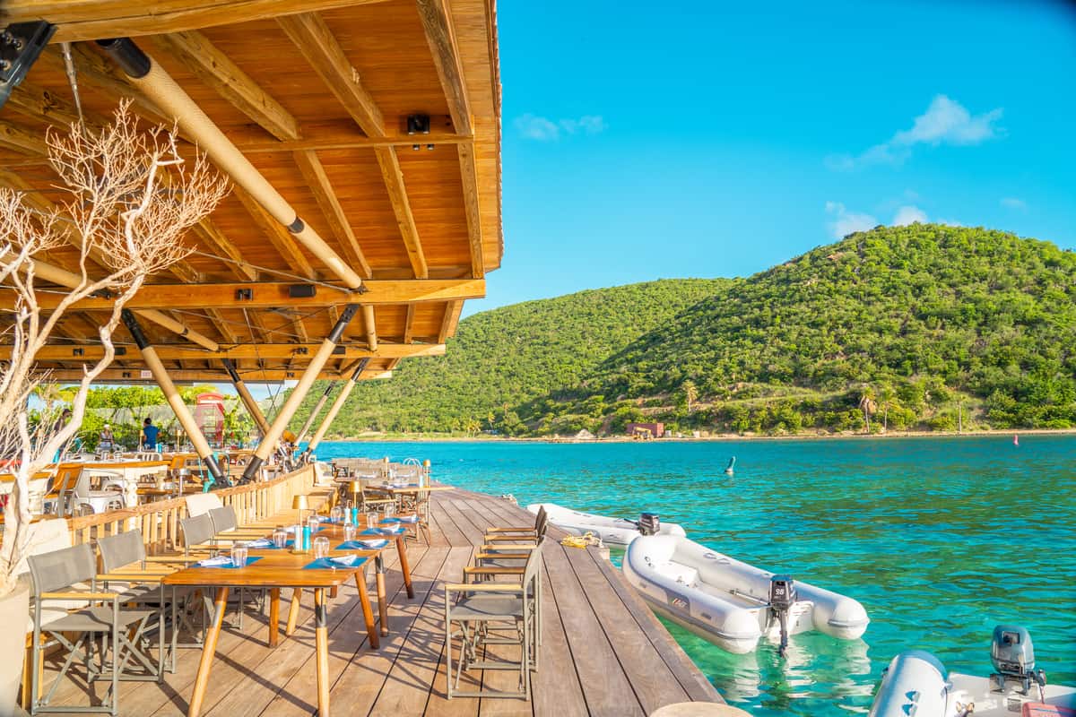 a wooden deck with tables and chairs on a dock 