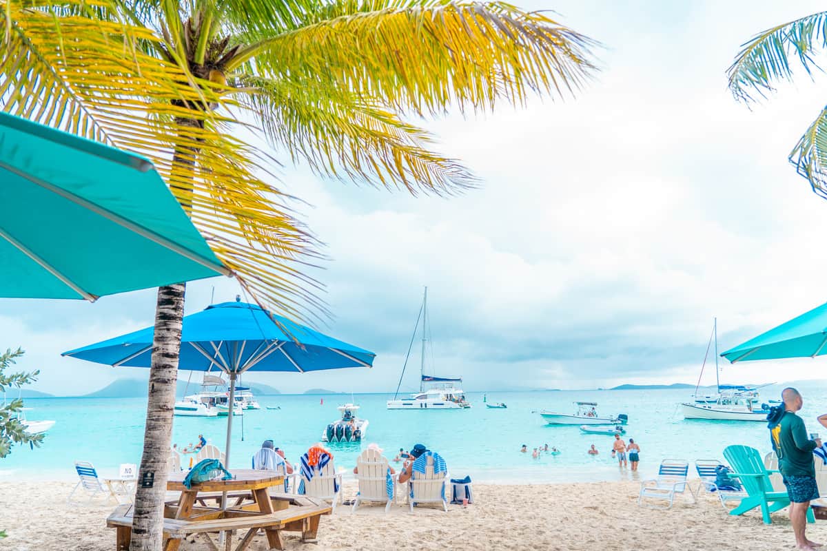 a beach with people and boats - british virgin islands vacation