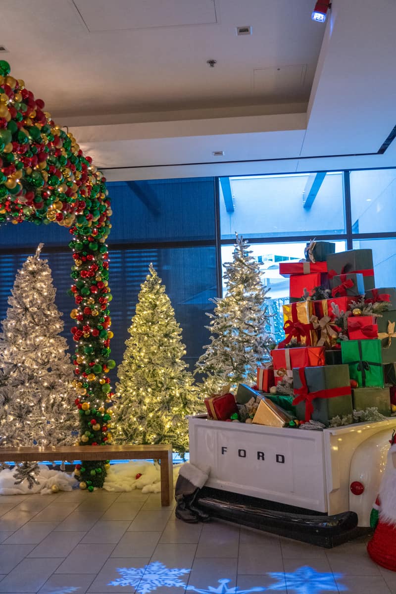 A display of christmas tress and gifts on a lobby.