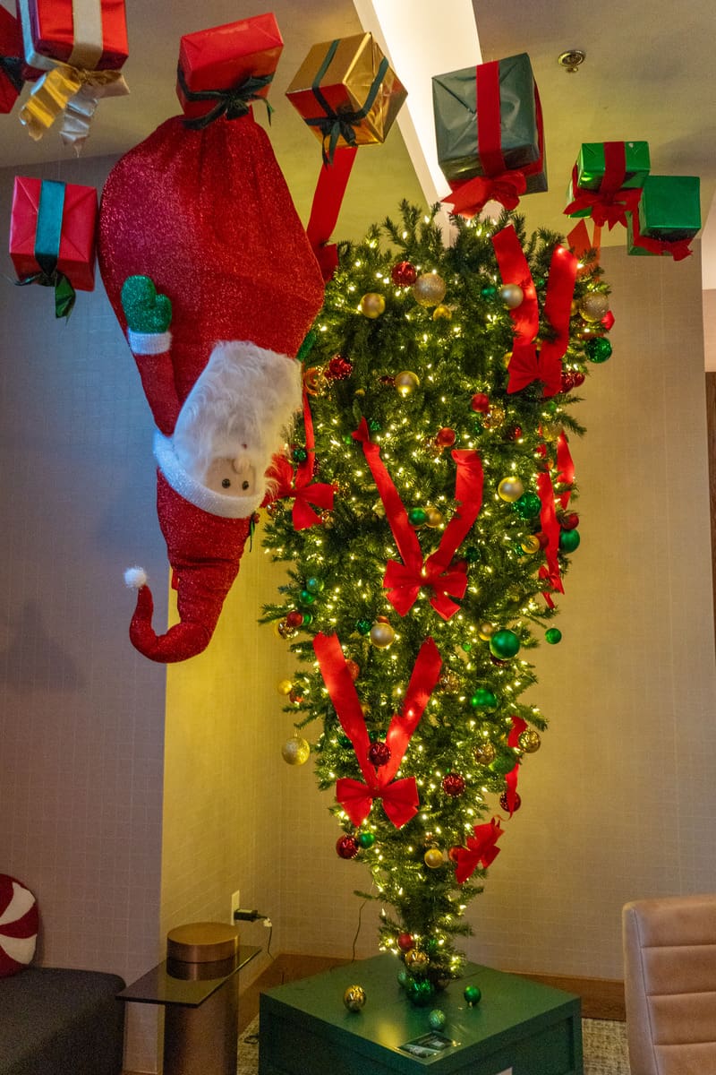 A festive cristmas tree and santa hanging upside down.