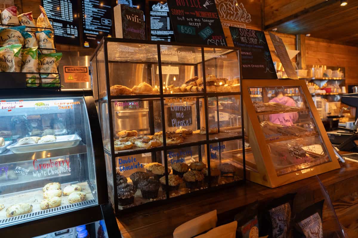A bakery case with muffins, Danishes, and other pastries inside with additional pastry cases on either side of it.