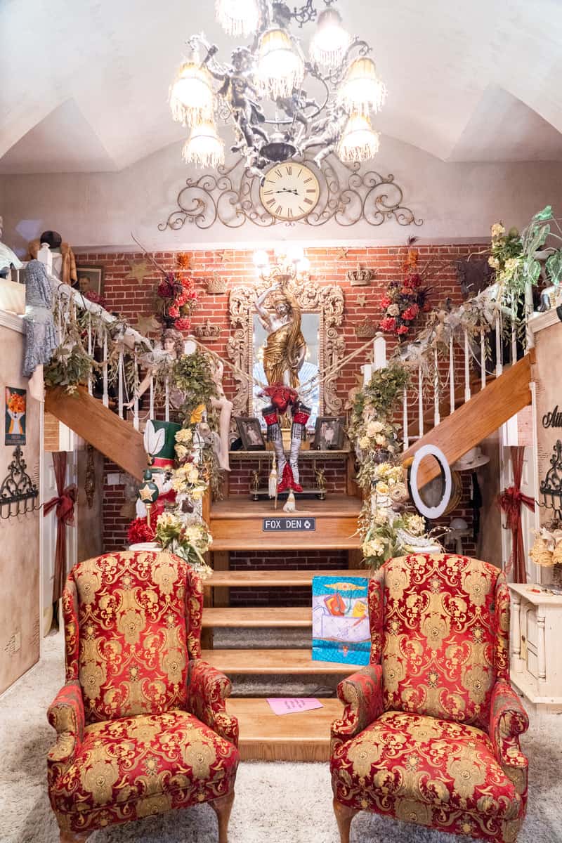 A bifurcating staircase with Christmas decorations on the railings. There is also a pair of red and gold armchairs at the base of the staircase.